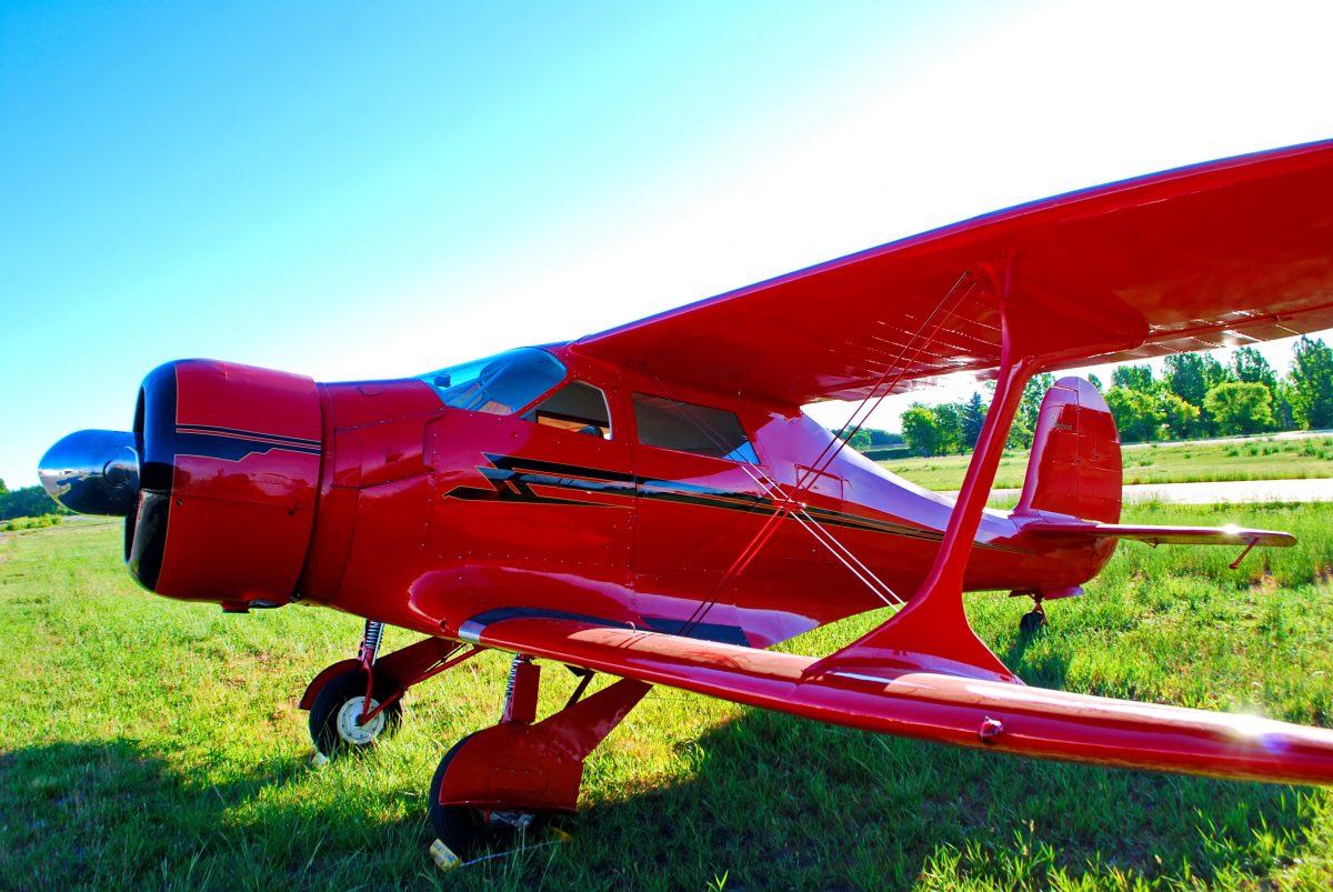 Red Beechcraft Staggerwing aircraft parked in grass runway in Idaho