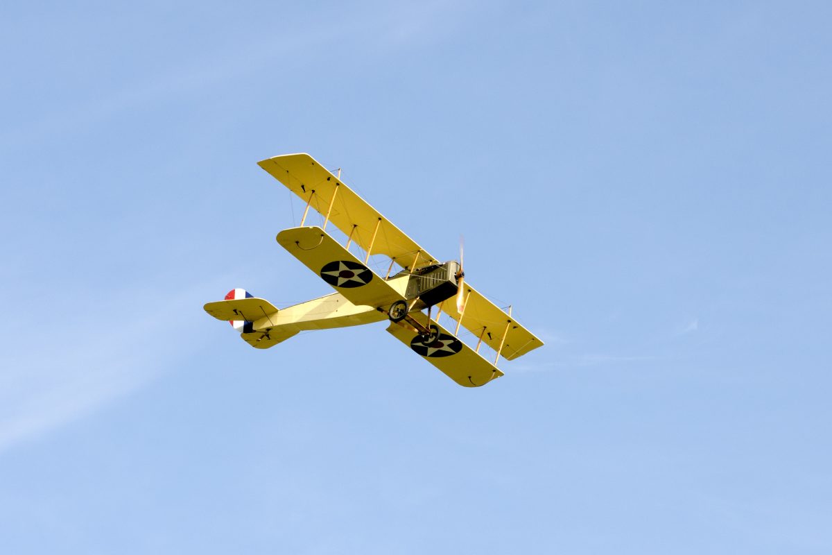 Flying Curtiss JN-4H biplane in Army Air Service colors of blue and yellow.