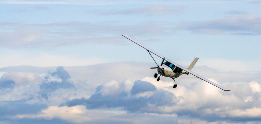 Propeller plane flying on the cloudy sky background