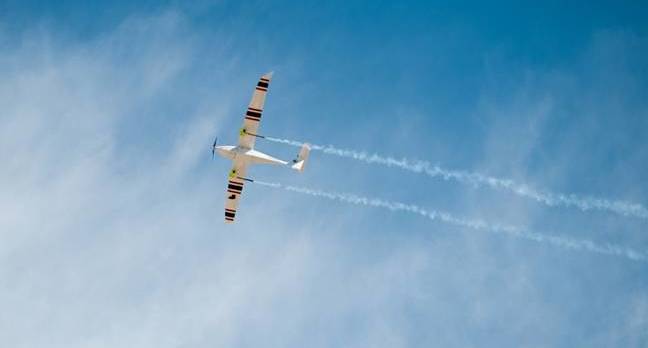 Upward view of white and red propeller-drive aircraft in flight