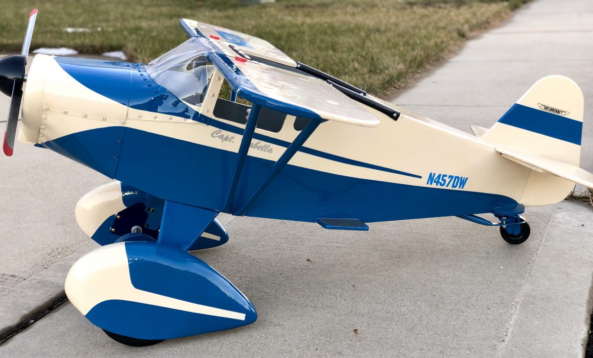 Blue and white Taylorcraft Pedal Plane facing sideways on the ground